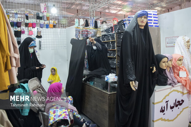 یکی از بازدید کنندگان به همراه فرزندان خود در حال بازدید از محصولات ارائه شده در نمایشگاه عفاف و حجاب است