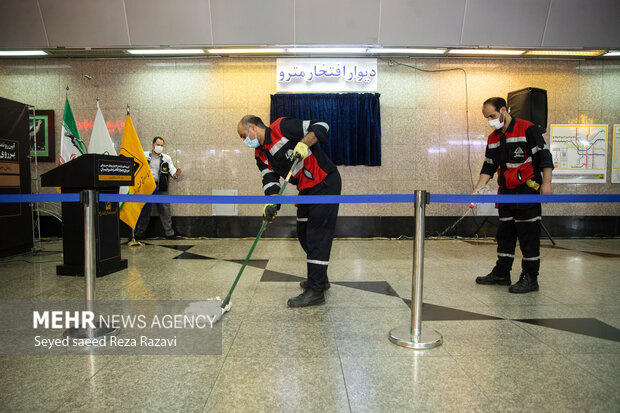 دو نفر از کارگران در حال تمیز کردن محل برگزاری آئین رونمایی از یادمان نام جهان پهلوان حسن یزدانی هستند 