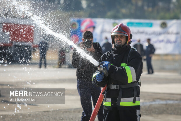 یکی از شرکت کنندگان مسابقه در حال هدف زنی با آب در مسابقات ورزشی آتش نشانان نیروی هوایی ارتش است