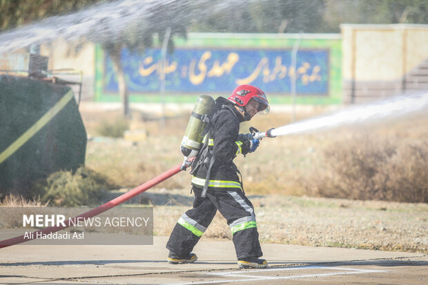 یکی از شرکت کنندگان مسابقه در حال هدف زنی با آب در مسابقات ورزشی آتش نشانان نیروی هوایی ارتش است