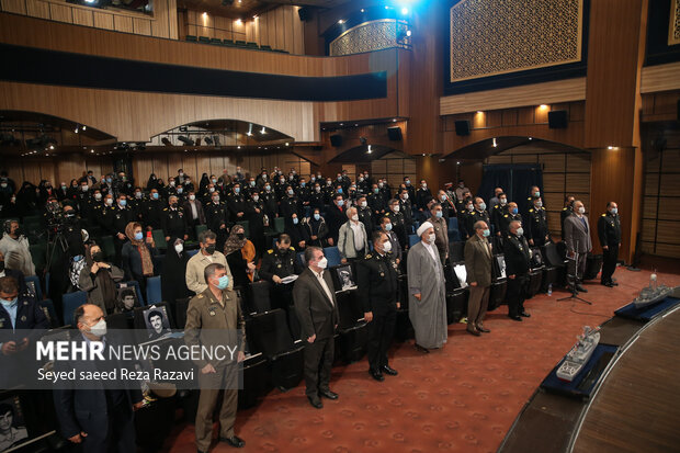 امیر شهرام ایرانی فرمانده نیروی دریایی ارتش و دیگر مهمانان حاضر در سالن در ابتدای مراسم در حال ادای احترام به سرود جمهوری اسلامی ایران هستند