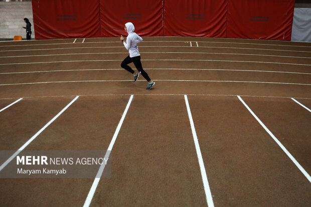 ورزشکار شرکت کننده در مسابقات دو و میدانی داخل سالن قهرمانی کشور در حال مسابقه است