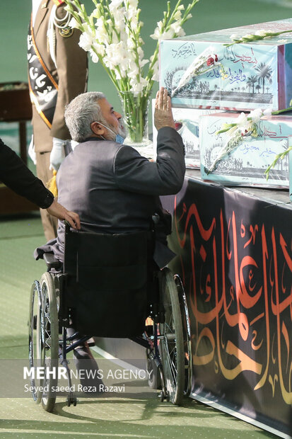  یک جانباز دفاع مقدس در حال وداع با پیکرهای مطهر ۱۵۰ شهید گمنام دوران هشت سال دفاع مقدس در مصلای تهران است