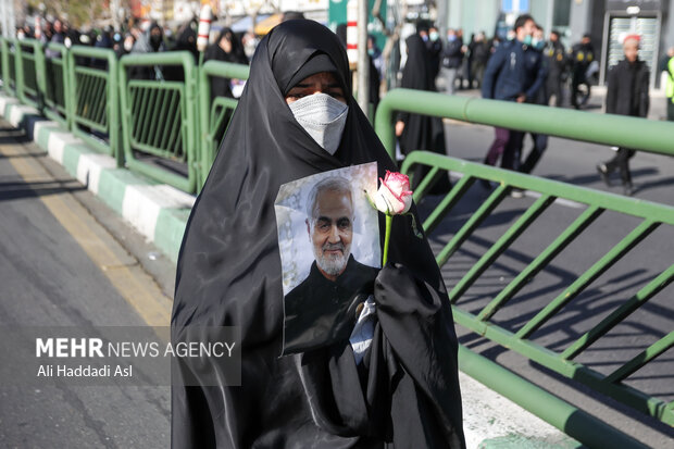 یکی از حاضران در تشییع پیکرهای مطهر ۱۵۰ شهید گمنام دفاع مقدس تصویر شهید حاج قاسم سلیمانی را در دست دارد