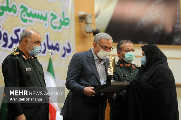 بهرام عین‌اللهی وزیر بهداشت کرمان در همایش تقدیر از دست اندر کاران طرح شهید سلیمانی در حال تقدیر از یکی از برگزیدگان این طرح است