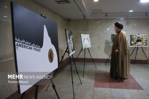 یکی از روحانیون حاضر در مراسم رونمایی از کتاب جهاد تبیین در حال بازدید از نمایشگاه پوستر در حاشیه این مراسم است