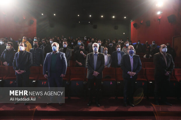 مدعوین حاضر در آئین قرعه کشی برنامه نمایش فیلم ها  در خانه جشنواره فجر در حال ادای  احترام به سرود ملی جمهوری اسلامی ایران هستند