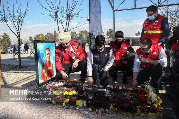  تعدادی از آتش نشانان با حضور بر مزار شهدای آتش نشان حادثه پلاسکو در حال ادای احترام و قرائت فاتحه هستند 