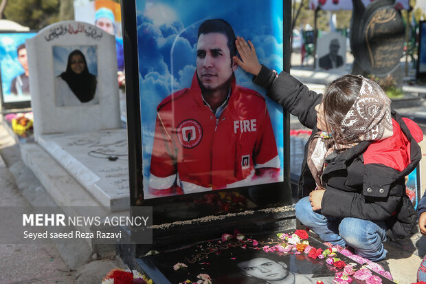    یک کودک خردسال در حال ادای احترام به یکی از شهدای آتش نشان است 