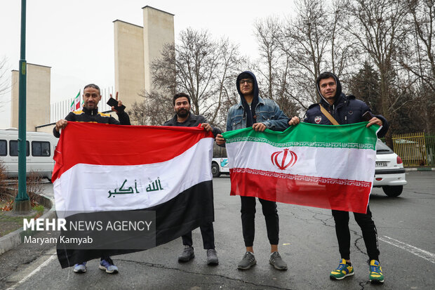 پرچم کشورهای ایران و عراق در دست تماشاگران در مقابل ورزشگاه آزادی است