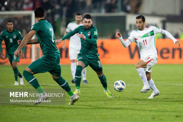 وحید امیری در حال عبور توپ از بازیکن تسم ملی فوتبال عراق در دیدار تیم های ملی فوتبال ایران و عراق است