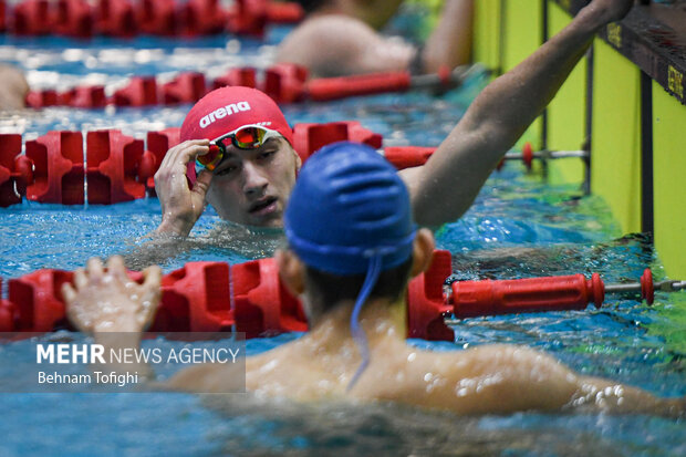 دونفر از شناگران حاظر در مرحله دوم هجدهمین دوره لیگ برتر شنا در خط پایان مسابقه در حال گفتگو با یکدیگر هستند