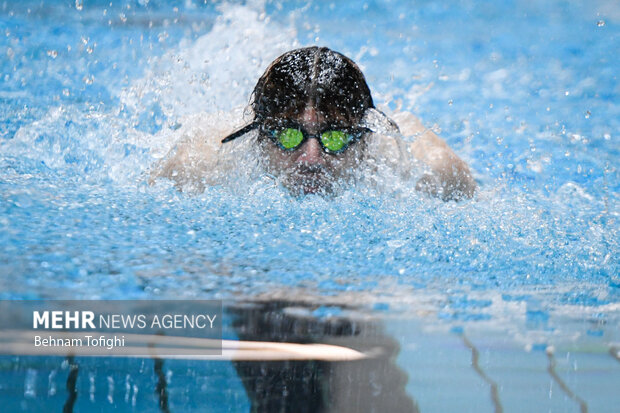 یکی از شناگران حاظر در مرحله دوم هجدهمین دوره لیگ برتر شنا در حال رقابت با سایر شناگران است