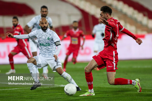 مهدی عبدی بازیکن تیم فوتبال پرسپولیس تهران در حال عبور توپ از مدافع تیم فوتبال آلومینیوم اراک در دیدار تیم های فوتبال پرسپولیس تهران و  آلومینیوم اراک است