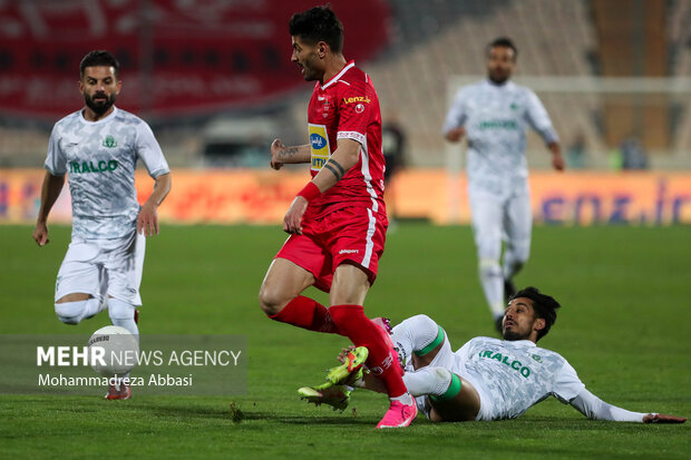 سعید اقایی بازیکن تیم فوتبال پرسپولیس تهران در حال عبور توپ از مدافع تیم فوتبال آلومینیوم اراک در دیدار تیم های فوتبال پرسپولیس تهران و  آلومینیوم اراک است