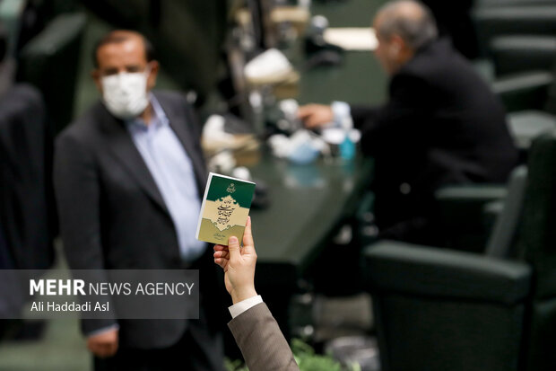 یک نماینده کتاب آئین نامه داخلی مجلس شورای اسلامی را در صحن علنی در دست گرفته دست