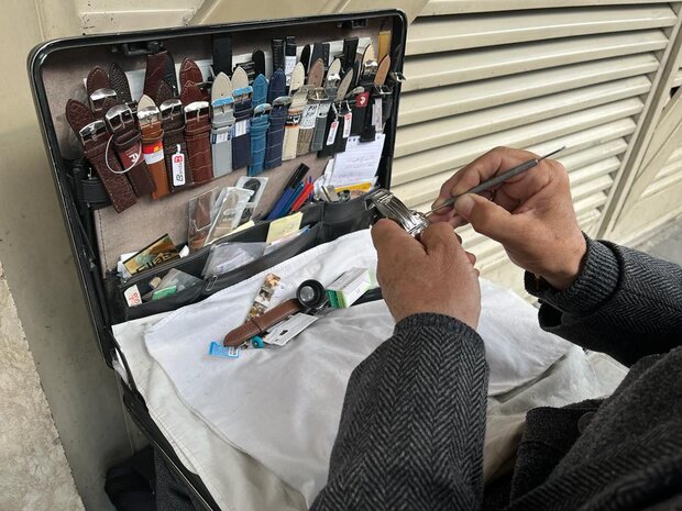 معلم افغانستانی که کنار خیابان ساعت تعمیر می‌کند