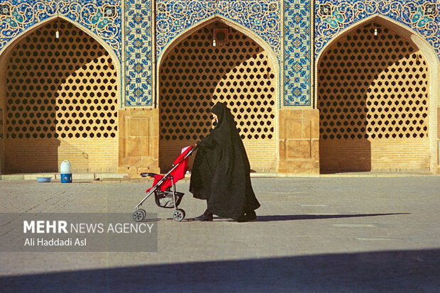 مادری به همراه فرزندش در حال عبور از محوطه باز مسجد است