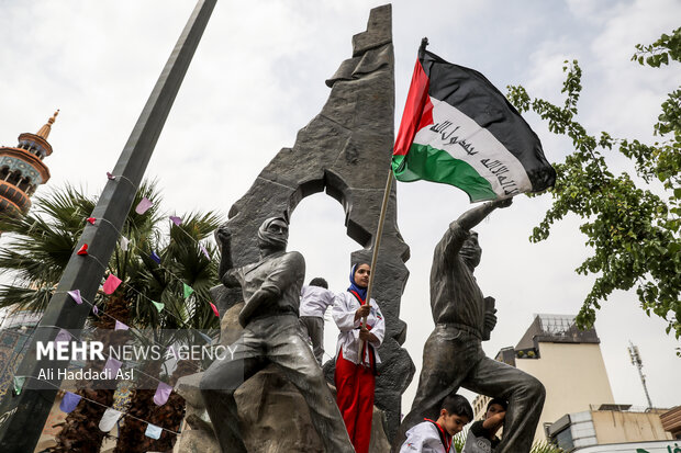 دختر خردسالی در مراسم راهپیمایی روز جهانی <a href='https://sayeb.ir/tag/%d9%82%d8%af%d8%b3'>قدس</a> بر بلندای مجسمه میدان فلسطین پرچم این کشور را برافراشته است
