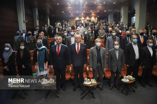 حاضرین در مراسم هشتادمین سالگرد ورود پناهندگان لهستانی به ایران در حال ادای احترام به سرود ملی جمهوری اسلامی ایران هستند