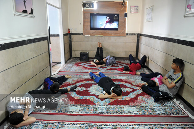 کودکان کار مرکز یاسر در زمان استراحت در حال تماشای تلویزیون هستند