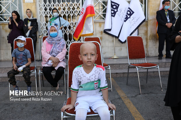 یک کودک مبتلا به بیماری مزمن در مراسم چهارمین دوره مسابقات فوتبال جام جهانی کوچک در تصویر دیده میشود
