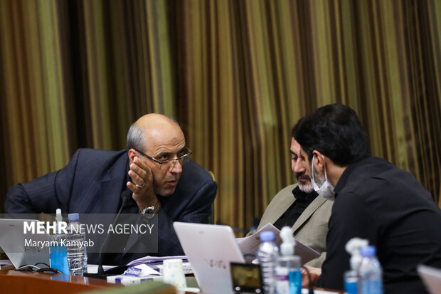 اعضای شورای شهر تهران در حال گفتگو با یکدیگر در جلسه شورای اسلامی شهر تهران هستند