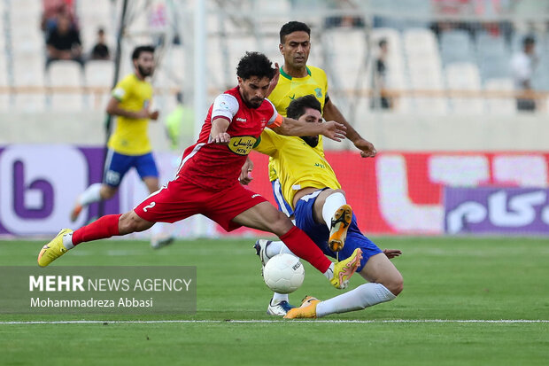 امید عالیشاه بازیکن تیم فوتبال پرسپولیس تهران در حال عبور توپ از مدافع تیم فوتبال صنعت نفت آبادان است