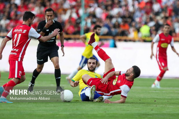 بازیکن تیم فوتبال صنعت نقت آبادان در حال گرفتن توپ از سروش رفیعی هافک تیم فوتبال پرسپولیس تهران است