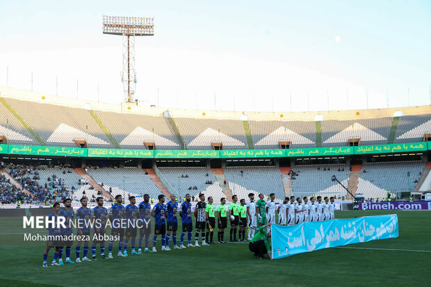 دو تیم فوتبال  استقلال تهران و پیکان تهران در حال انجام تشریفات پیش از شروع مسابقه در ورزشگاه آزادی تهران هستند