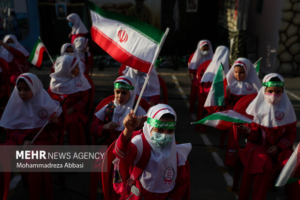 یکی از دانش آموزان در مراسم آغاز سال تحصیلی جدید با حضور رییس جمهور پرچم ایران را در دست دارد