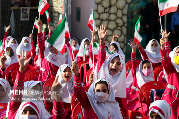 دانش آموزان در مراسم آغاز سال تحصیلی جدید با حضور رییس جمهور پرچم ایران حضور دارند