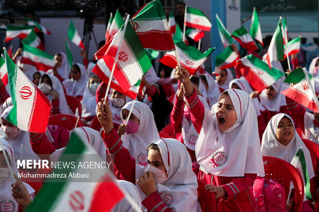 دانش آموزان در مراسم آغاز سال تحصیلی جدید با حضور رییس جمهور پرچم ایران حضور دارند