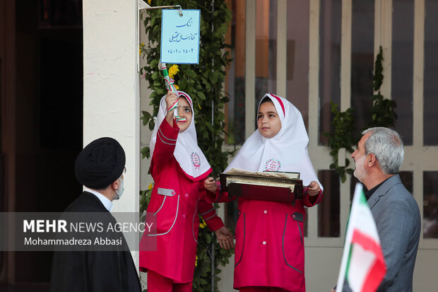 دو نفر از دانش آموزان در حضور حجت الاسلام سید ابراهیم رئیسی ، رئیس جمهور و یوسف نوری وزیر آموزش و پرورش در حال نواختن زنگ آغاز سال تحصیلی جدید هستند