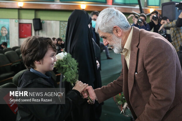 پدر شهید مصطفی احمدی روشن در حال اهدای دسته گلی به فرزند شهیدسید فرید معصومی  است 