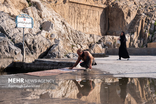 یکی از اهالی شهرری از صبح زود مشغول شست شوی فرش ها در چشمه علی هستند