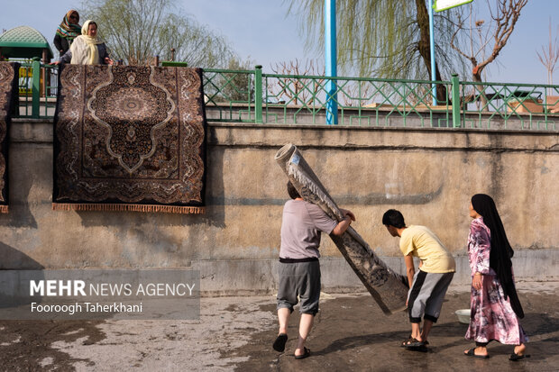 خانواده ای هل ری بعد شستن فرش خود در چشمه علی آن را برای کشیده شدن آب روی نرده ها می اویزد