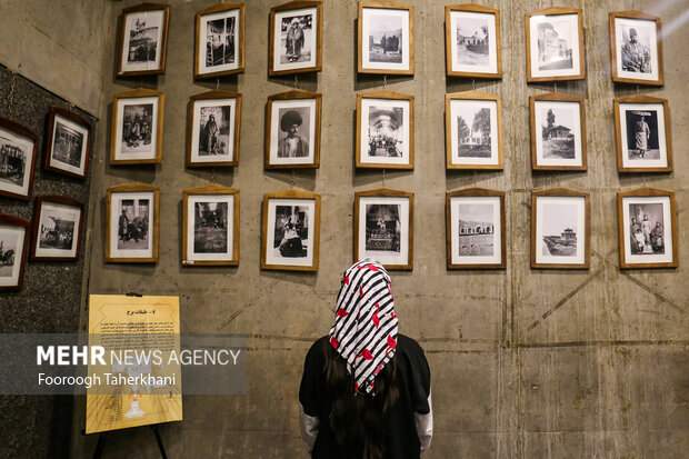 بازدید کننده از عکس های قدیمی در تالار قسمت پایین برج آزادی بازدید میکند