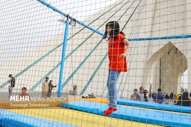 کودکی درتعطیلات عید نوروز با وسایل تفریحی پایین برج بازی میکند