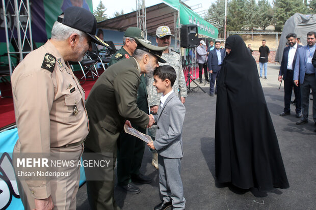 سرتیپ محمدرضا قرایی آشتیانی وزیر دفاع در حال تجلیل از خانواده  شهدا در مراسم رونمایی از موشک راهبردیِ بُرد بلند و نقطه زن خرمشهر ۴ است