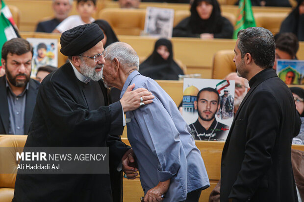 حجت الاسلام سید ابراهیم رئیسی، رئیس جمهور در مراسم ملی بزرگداشت شهدای مدافع حرم در حال گفتگو با خانواده شهدا است