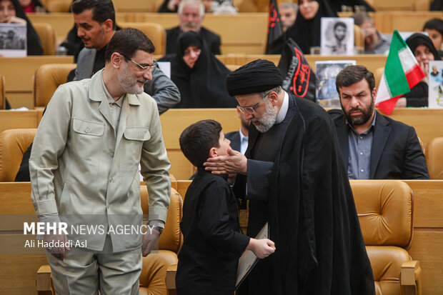 حجت الاسلام سید ابراهیم رئیسی، رئیس جمهور در مراسم ملی بزرگداشت شهدای مدافع حرم در حال گفتگو با خانواده شهدا است