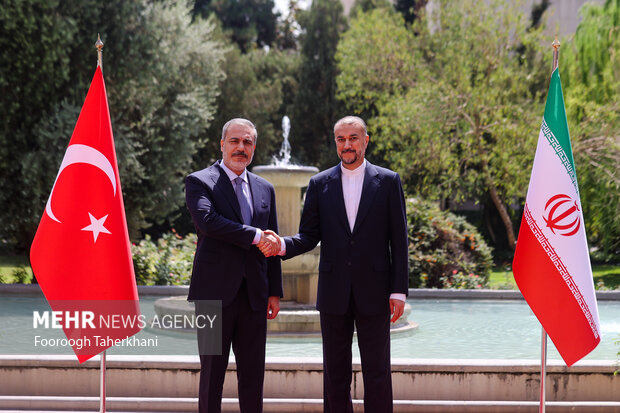 حسین امیر عبداللهیان، وزیر امور خارجه ایران و هاکان فیدان، وزیر امور خارجه ترکیه در حال گرفتن عکس یادگاری در محل دیدار وزرای خارجه ترکیه و ایران هستند