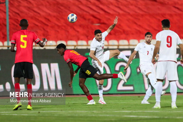 علی کریمی بازیکن تیم ملی فوتبال ایران در حال عبور توپ از کلیانو منوال بازیکن تیم ملی فوتبال آنگولا در دیدار تیم های ملی فوتبال ایران و آنگولا هستند 