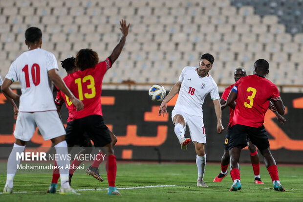 علی کریمی بازیکن تیم ملی فوتبال ایران در حال عبور توپ از بازیکنان تیم ملی فوتبال آنگولا در دیدار تیم های ملی فوتبال ایران و آنگولا هستند 