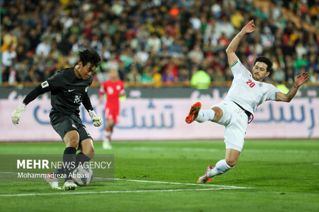 دروازبان تیم ملی فوتبال هنگ کنگ در حال عبور توپ از مقابل درو.ازه خود در دیدار تیم های ملی فوتبال ایران و هنگ کنگ است