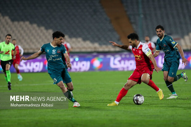 امید عالیشاه بازیکن تیم فوتبال پرسپولیس تهران در حال عبور توپ از مدافعین تیم فوتبال شمس آذر قزوین در دیدار تیم های فوتبال پرسپولیس تهران و شمس آذر قزوین است