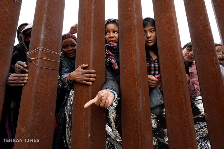 Migrants and refugees reach for clothing handed out by volunteers as they wait between two border walls to apply for asylum on May 12. The US entered a new immigration enforcement era, ending three-year-old asylum restrictions. [Gregory Bull/AP Photo]
