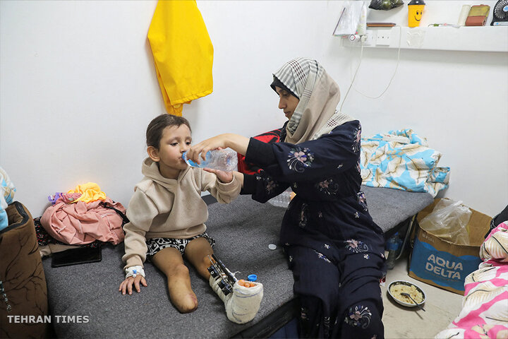 Palestinian girl Eman Al-Kholi, whose limb was amputated after being wounded in an Israeli strike that killed her parents, is helped to drink water as she receives treatment at the European Hospital, in Rafah. More than 1,000 children have reportedly lost one or both legs since October 7. [Arafat Barbakh/Reuters]
