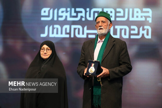 همسر شهید علی محمدی نشان استقلال را به سید حسین حسینی‌ آزاد در مراسم اختتامیه جشنواره فیلم عمار اهدا میکند